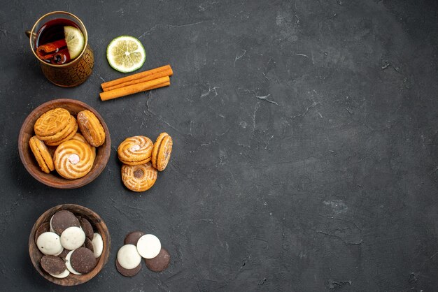 Bovenaanzicht kopje thee met verschillende koekjes op donkere ondergrond