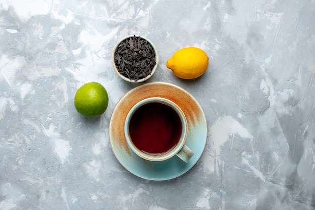 Bovenaanzicht kopje thee met verse citroenen en gedroogde thee op de lichttafel, thee fruit citrus kleur