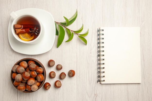 Bovenaanzicht kopje thee met verse hazelnoten op witte bureau thee noot snack ceremonie