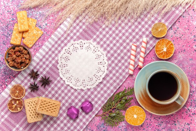 Bovenaanzicht kopje thee met wafels en crackers op roze