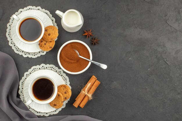 Bovenaanzicht kopjes koffie cinnamons cookies melk kopje cacaopoeder in kom op donkere ondergrond