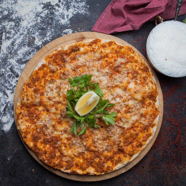 Bovenaanzicht lahmacun met peterselie en citroen en doek en ayran in houten voedsel lade