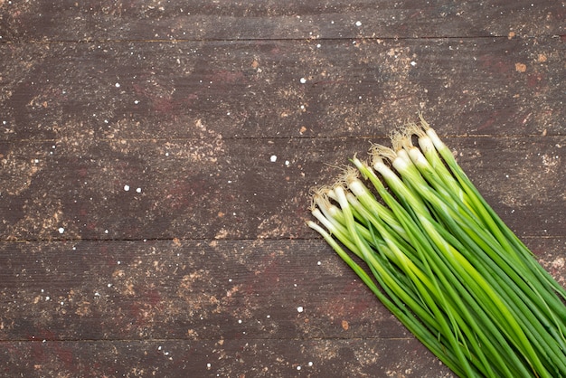 Bovenaanzicht lange groene ui op bruin, groen blad salade