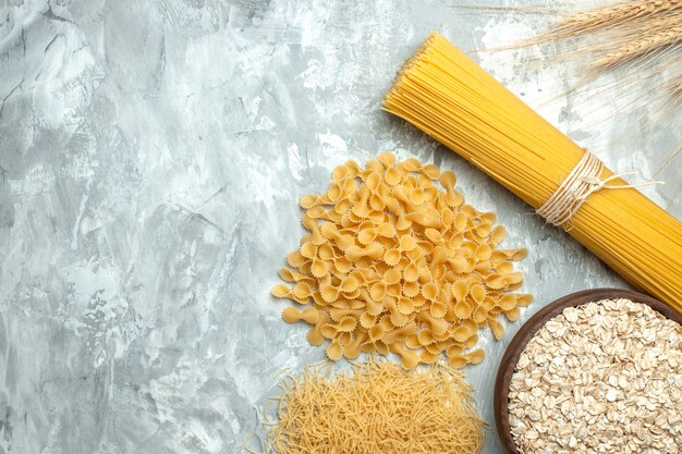 Bovenaanzicht lange Italiaanse pasta met verschillende gevormde rauwe kleine pasta op lichte achtergrond
