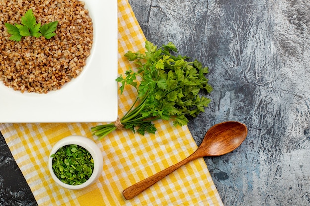 Bovenaanzicht lekker gekookt boekweit binnen bord met greens op lichtgrijze tafel