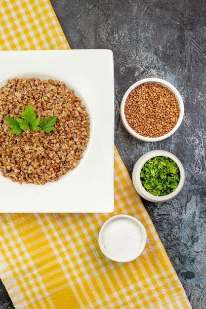 Bovenaanzicht lekker gekookt boekweit in witte plaat met greens op lichtgrijze tafel