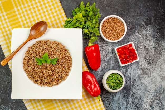 Bovenaanzicht lekker gekookt boekweit met groentjes en paprika op de lichtgrijze tafel