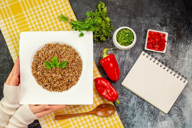 Bovenaanzicht lekker gekookt boekweit met groentjes en paprika op de lichtgrijze tafel