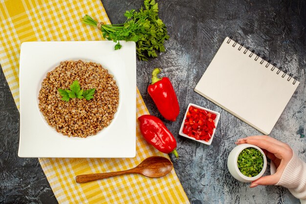 Bovenaanzicht lekker gekookt boekweit met groentjes en paprika op de lichtgrijze tafel