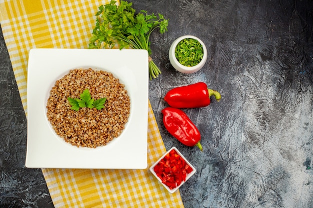 Bovenaanzicht lekker gekookt boekweit met groentjes en paprika op de lichtgrijze tafel