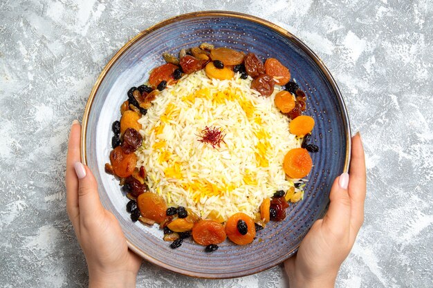 Bovenaanzicht lekker shakh plov gekookte rijstgerecht met rozijnen in plaat op licht wit