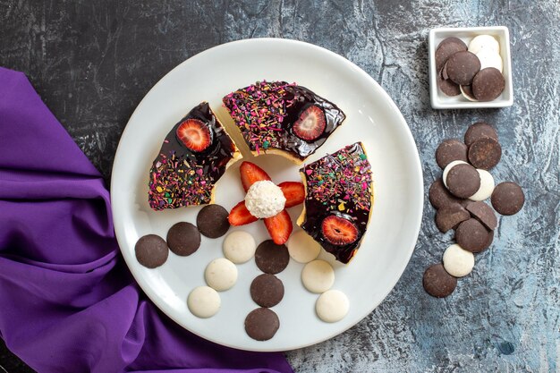 Bovenaanzicht lekkere cakeplakken met chocokoekjes op donkere ondergrond