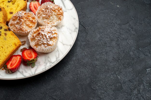 Bovenaanzicht lekkere cakeplakken met verse rode aardbeien en koekjes op grijze ondergrond cake bakken biscuit taart suiker zoete koekjes