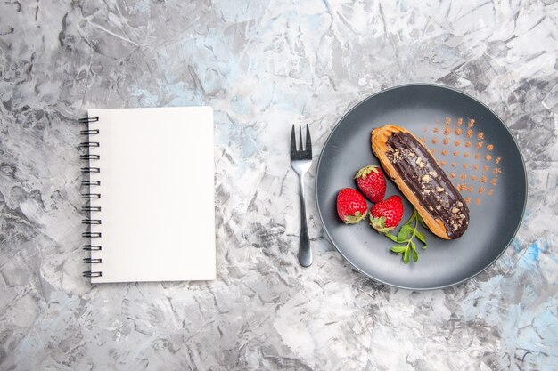 Bovenaanzicht lekkere choco eclairs met aardbeien op het lichte cake dessert snoep