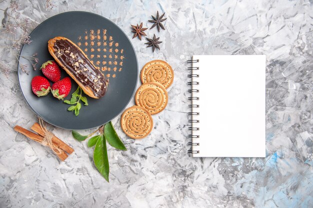 Bovenaanzicht lekkere choco eclairs met koekjes op licht bureau biscuit cake dessert cookie