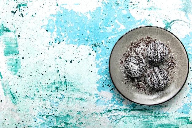Bovenaanzicht lekkere chocolade ballen chocolade taarten rond gevormd met glazuur op het blauwe bureau