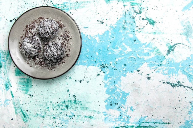 Bovenaanzicht lekkere chocolade ballen chocolade taarten rond gevormd met glazuur op het blauwe oppervlak