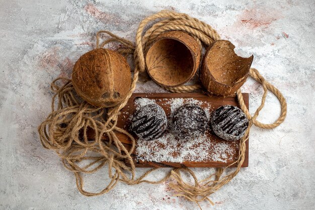 Gratis foto bovenaanzicht lekkere chocoladetaarten met kokos op het lichtwitte oppervlak