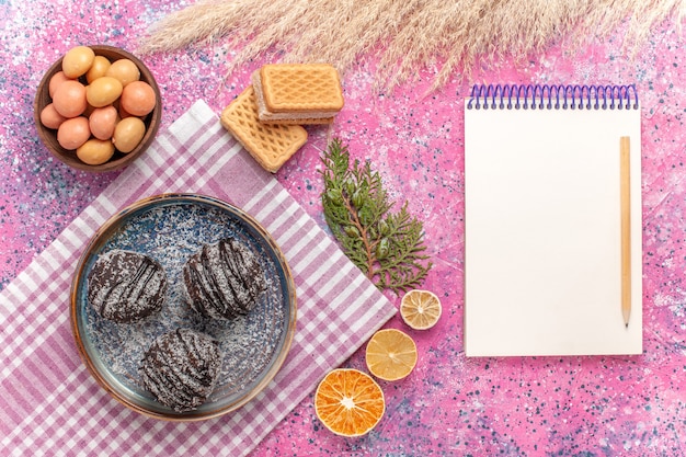 Bovenaanzicht lekkere chocoladetaarten met snoep en wafels op roze