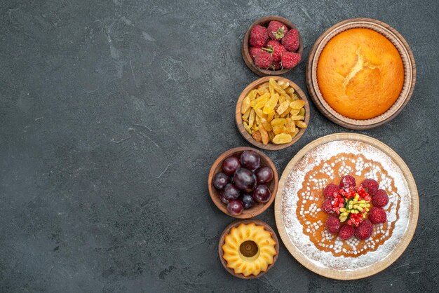 Bovenaanzicht lekkere frambozencake met rozijnen en fruit op het grijze oppervlak taart thee biscuit cake cookie sweet