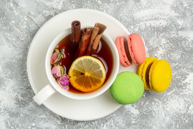 Bovenaanzicht lekkere Franse macarons kleurrijke taarten met kopje thee op witte ondergrond