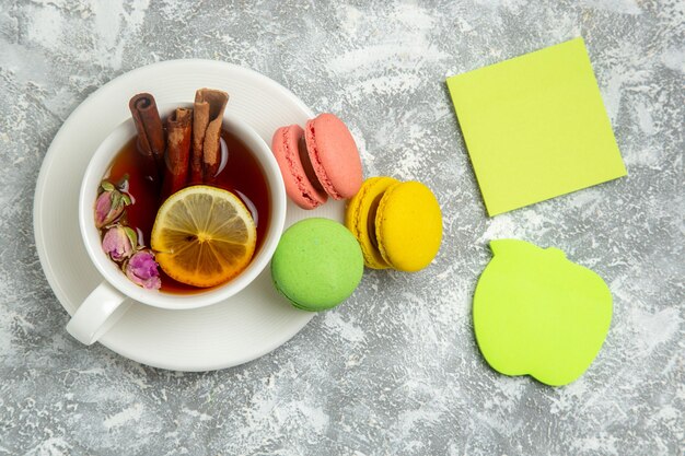 Bovenaanzicht lekkere Franse macarons kleurrijke taarten met thee op witte ondergrond