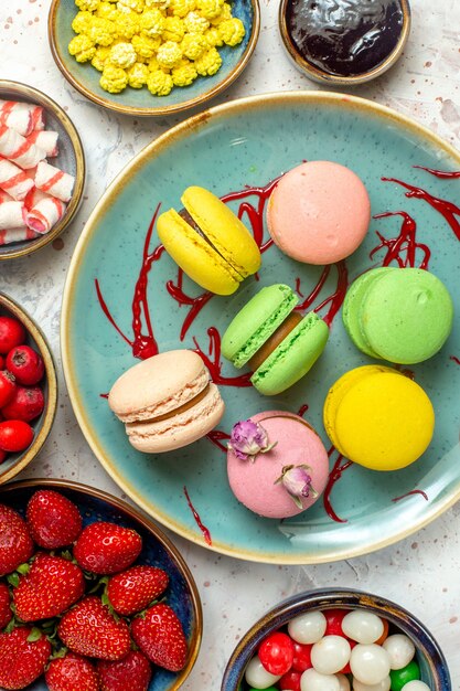 Bovenaanzicht lekkere franse macarons met bessen en snoepjes op witte cake zoete biscuit