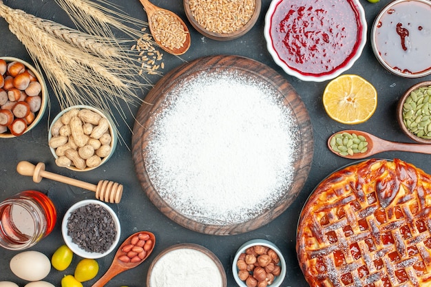 Bovenaanzicht lekkere fruitige taart met meel noten en jam op een donkere cookie zoete taart suiker taart thee gebak dessert biscuit