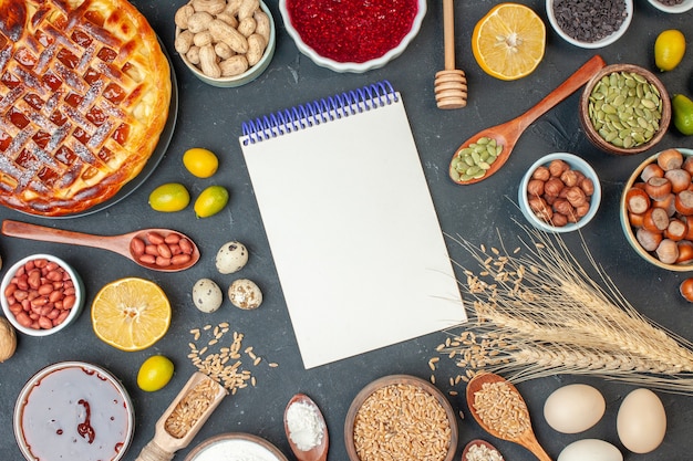 Bovenaanzicht lekkere fruittaart met notitieblok en noten op donkere kleur voedsel noten foto cake rozijn