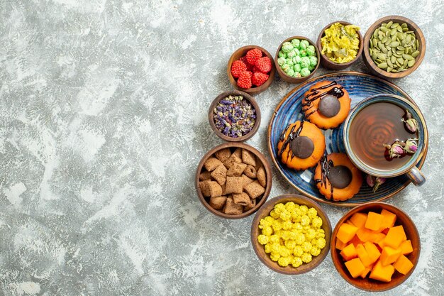 Bovenaanzicht lekkere kleine taarten met kopje thee op een wit oppervlak cake biscuit koekjes dessert zoete thee