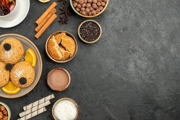 Bovenaanzicht lekkere koekjes met kopje thee op donkere oppervlakte cake taart suiker dessert biscuit thee koekje