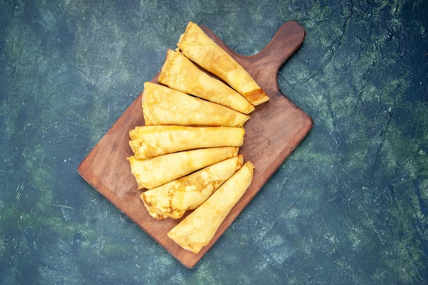 Bovenaanzicht lekkere pannenkoeken gerold op blauwe achtergrond taart zoet deeg vlees gebak kleur bakken