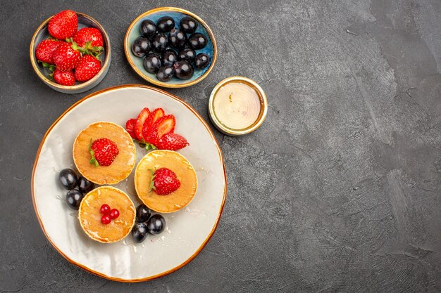 Bovenaanzicht lekkere pannenkoeken, klein gevormd met fruit op het grijs