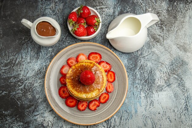 Bovenaanzicht lekkere pannenkoeken met aardbeien en honing op het licht