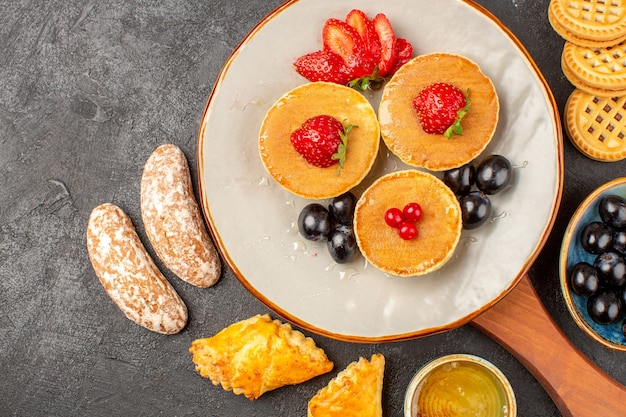 Bovenaanzicht lekkere pannenkoeken met fruit en gebak in het donker