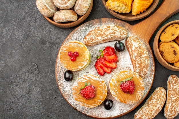 Gratis foto bovenaanzicht lekkere pannenkoeken met fruit en zoete taarten in het donker