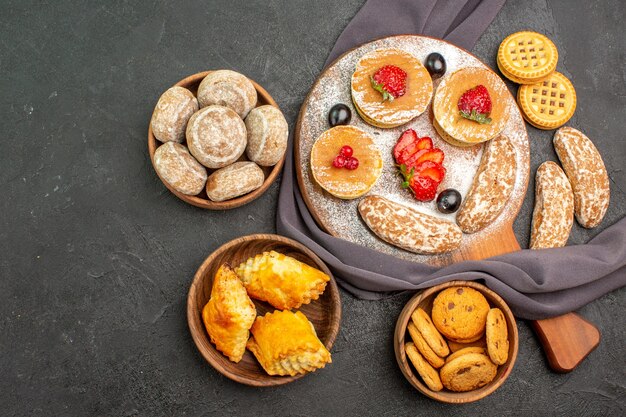 Bovenaanzicht lekkere pannenkoeken met fruit en zoete taarten in het donker