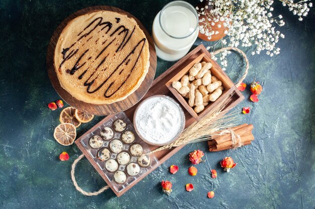 Bovenaanzicht lekkere pannenkoeken met melk en noten op donkerblauwe achtergrond ochtendtaart dessert zoete cake honing ontbijt melk