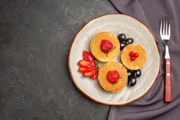 Bovenaanzicht lekkere pannenkoeken met olijven en fruit in het donker