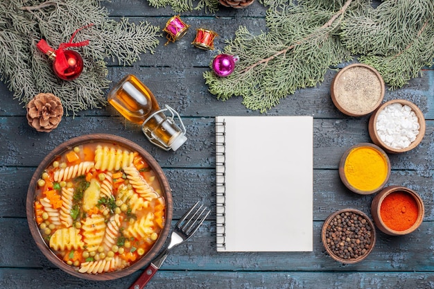 Bovenaanzicht lekkere pastasoep van spiraalvormige Italiaanse pasta met kruiden op de donkerblauwe bureaukeuken pastasoep diner kleurschotel