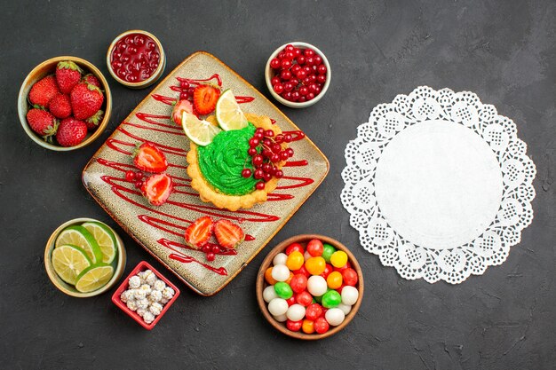 Bovenaanzicht lekkere romige cake met aardbeien op donkere bureau zoete suiker dessertthee