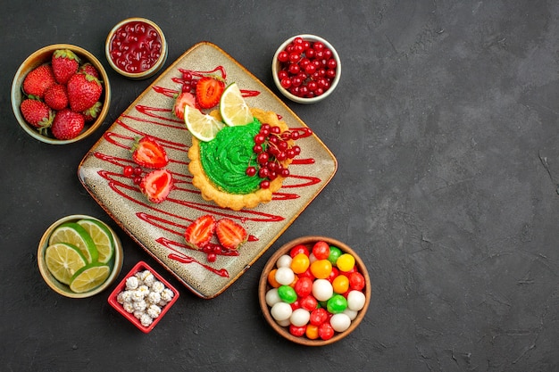 Bovenaanzicht lekkere romige cake met aardbeien op donkere vloer zoete suiker dessert thee