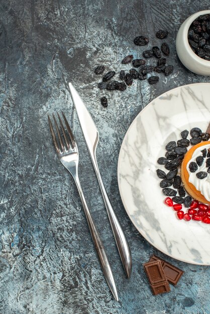 Bovenaanzicht lekkere romige cake met chocolade en rozijnen op licht-donkere achtergrond