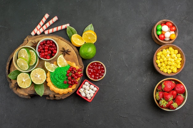 Bovenaanzicht lekkere romige cake met fruit op donkere achtergrond zoete koekjeskoekjes