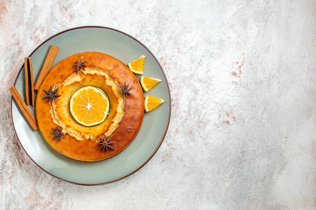 Gratis foto bovenaanzicht lekkere ronde taart heerlijk dessert voor thee met stukjes sinaasappel op witte achtergrond fruitcake taart biscuit thee zoet dessert