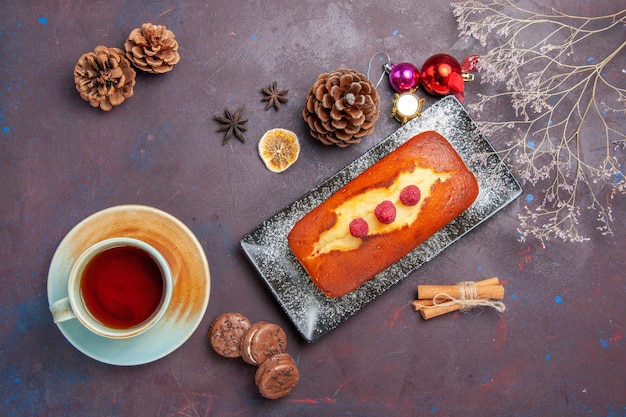 Bovenaanzicht lekkere taart lang gevormd met kopje thee op donkere ondergrond cake suiker koekjes taart zoete biscuit thee