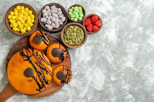 Bovenaanzicht lekkere taarten met chocoladesuikerglazuur en snoepjes op witte bureaucake cacaokoekjestaart dessert zoet koekje