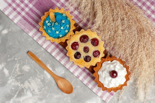 Bovenaanzicht lekkere taarten met room en fruit op de lichte ondergrond cake zoete room bak vruchtenthee