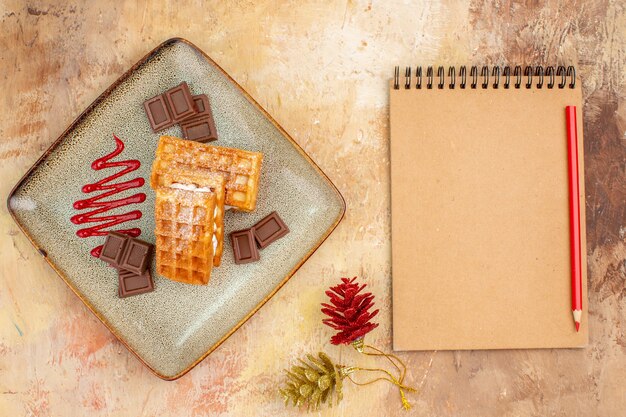 Bovenaanzicht lekkere wafelkoekjes met chocoladerepen op de bruine achtergrond