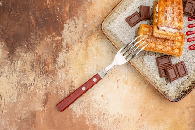 Bovenaanzicht lekkere wafelkoekjes met chocoladerepen op de bruine achtergrond